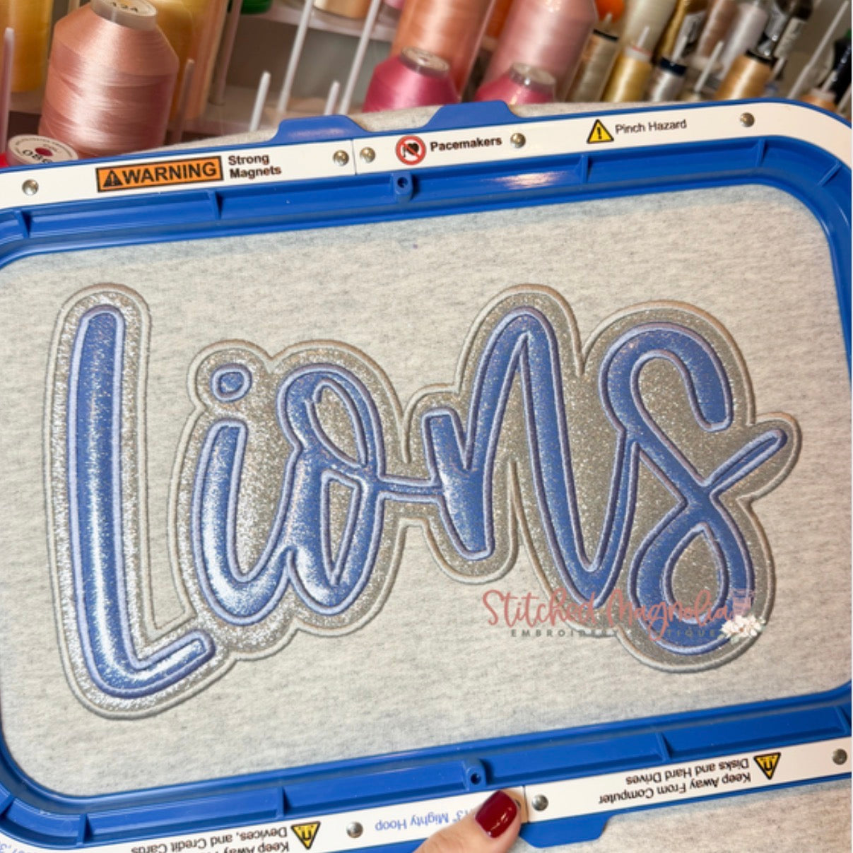 Blue and silver glitter Lions double stack appliqué with stitched outlines on an ash grey sweatshirt