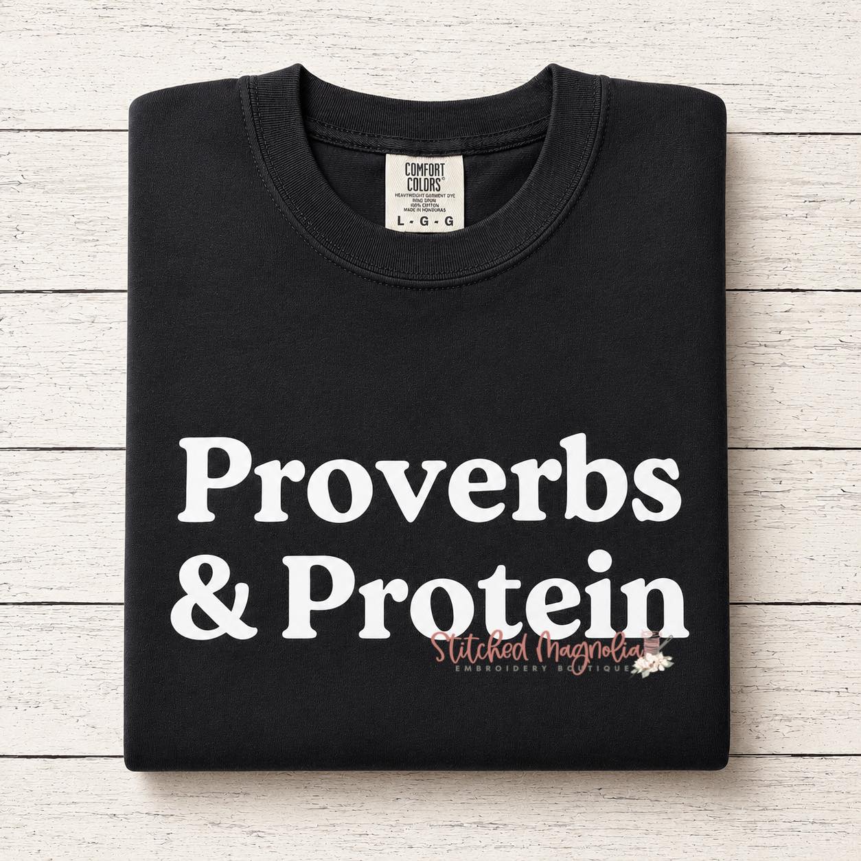 Proverbs & Protein graphic tee in black, folded, showing bold white text print
