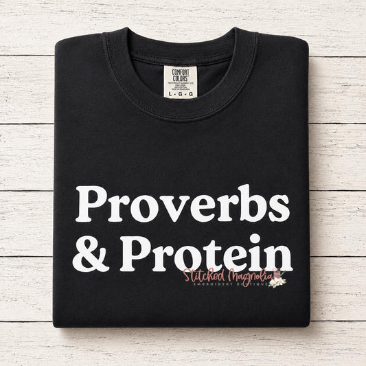 Proverbs & Protein graphic tee in black, folded, showing bold white text print